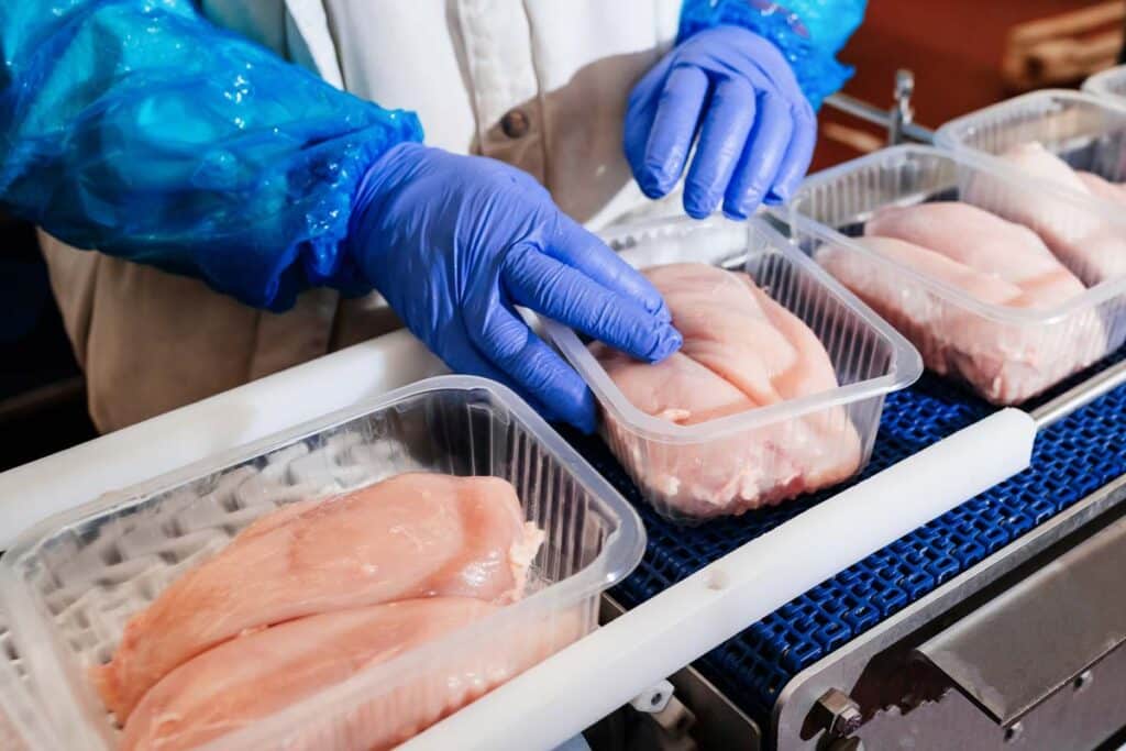 Close up of a worker packaging poultry, representing the poultry wage-fixing settlement.
