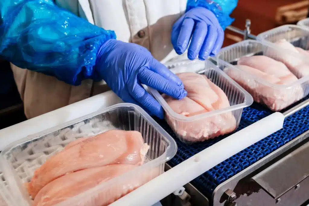 Close up of a worker packaging poultry, representing the poultry wage-fixing settlement.