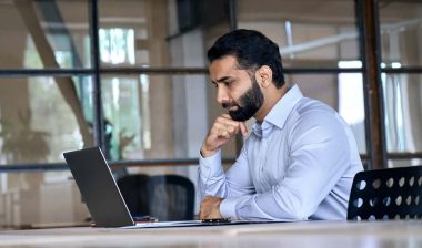 A man reading a publication on his laptop, representing the Charter Financial settlement.