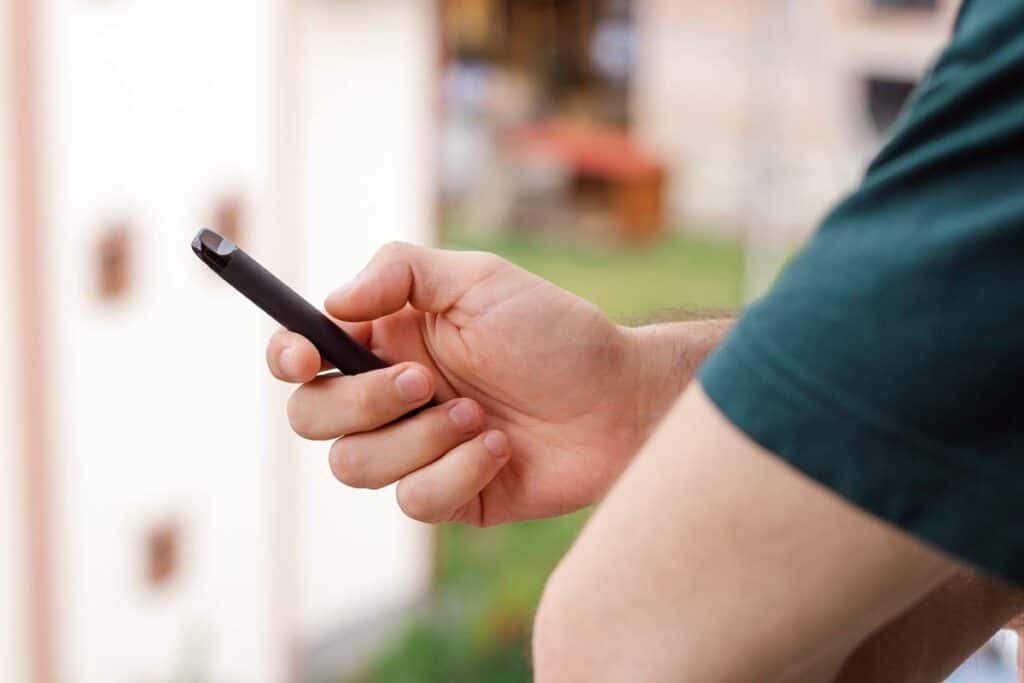 Close up of a man holding a black disposable cannabis vape, representing the Stiizy class action.