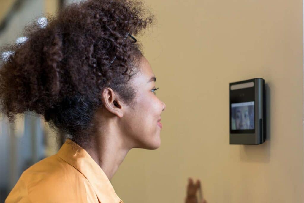 Close up of a woman using a face scanner on a wall, representing Amazon worker class action lawsuit.