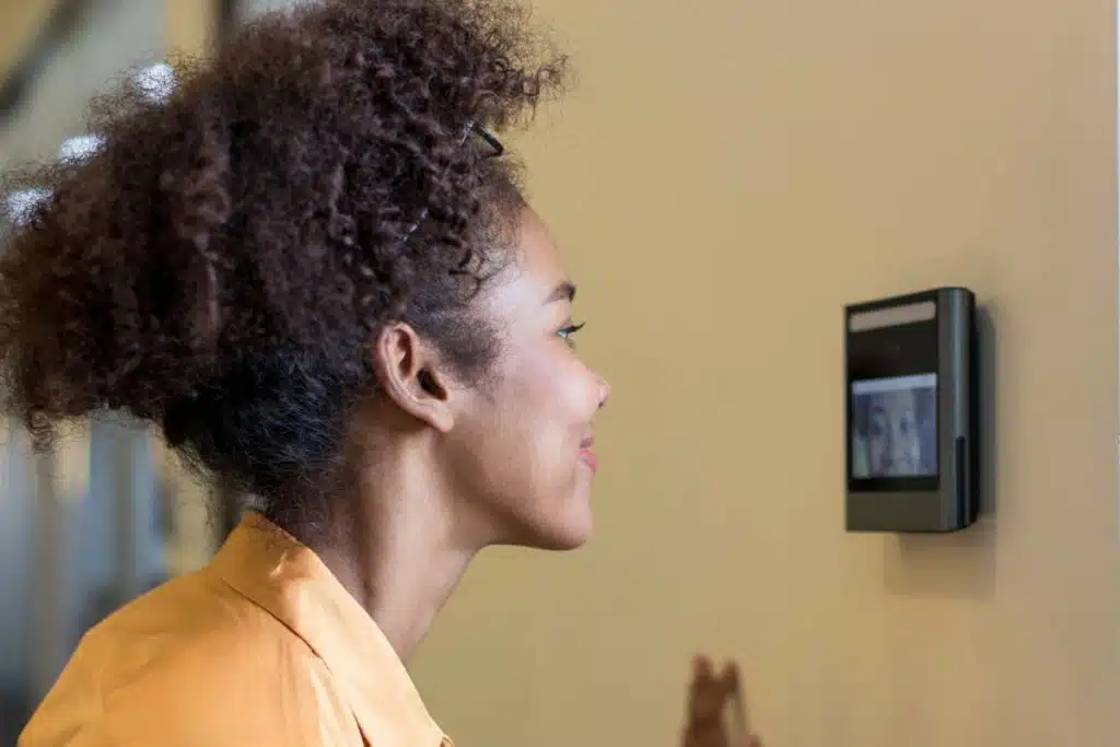 Close up of a woman using a face scanner on a wall, representing Amazon worker class action lawsuit.