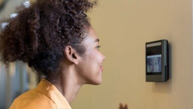 Close up of a woman using a face scanner on a wall, representing Amazon worker class action lawsuit.