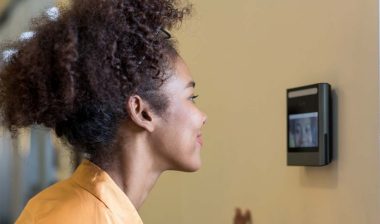 Close up of a woman using a face scanner on a wall, representing Amazon worker class action lawsuit.