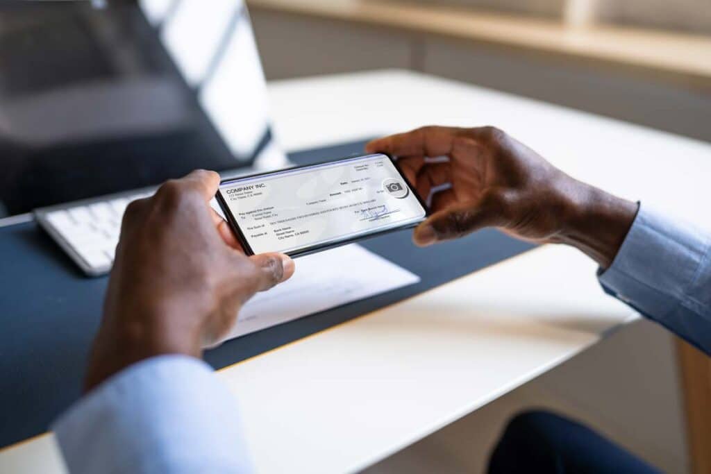 Close up of a check being deposited via mobile app, representing the banks class actions.