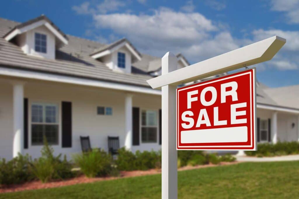 Close up of a for sale sign outside of a home, representing the Real Brokerage settlement.