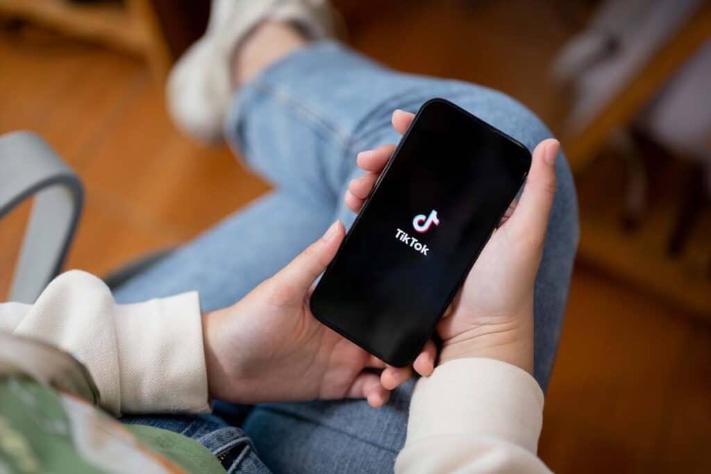 Close up of hands holding a smartphone with the TikTok logo displayed, representing the TikTok bill.