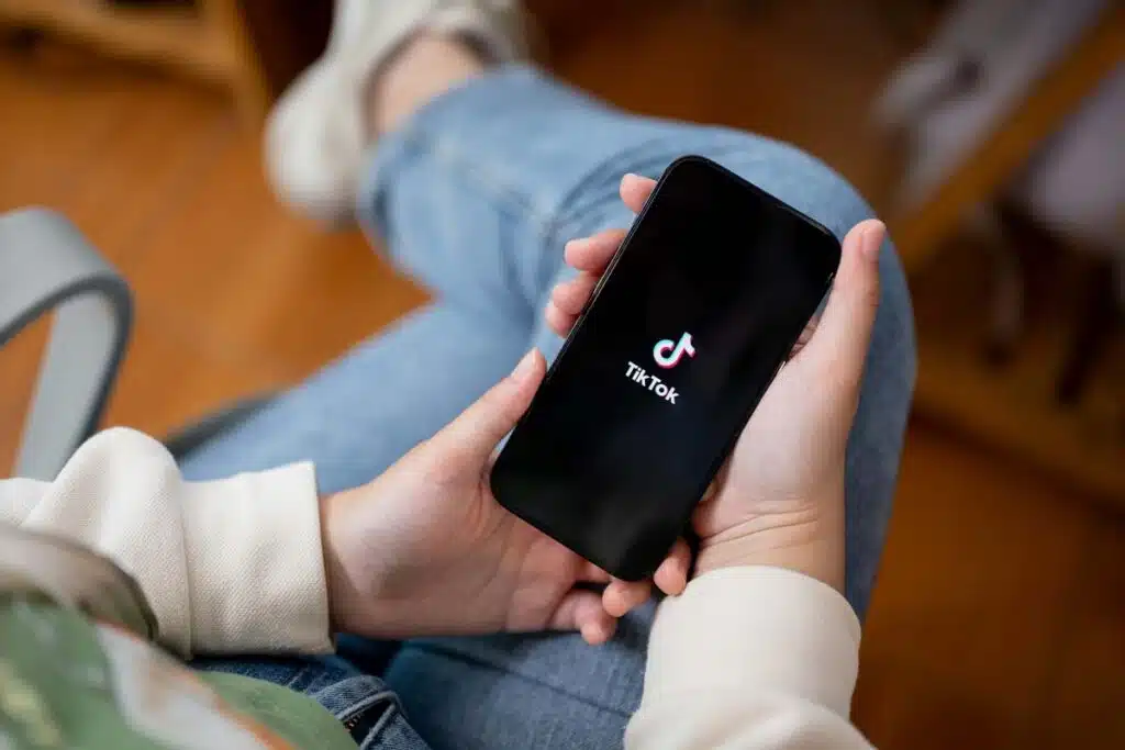 Close up of hands holding a smartphone with the TikTok logo displayed, representing the TikTok bill.