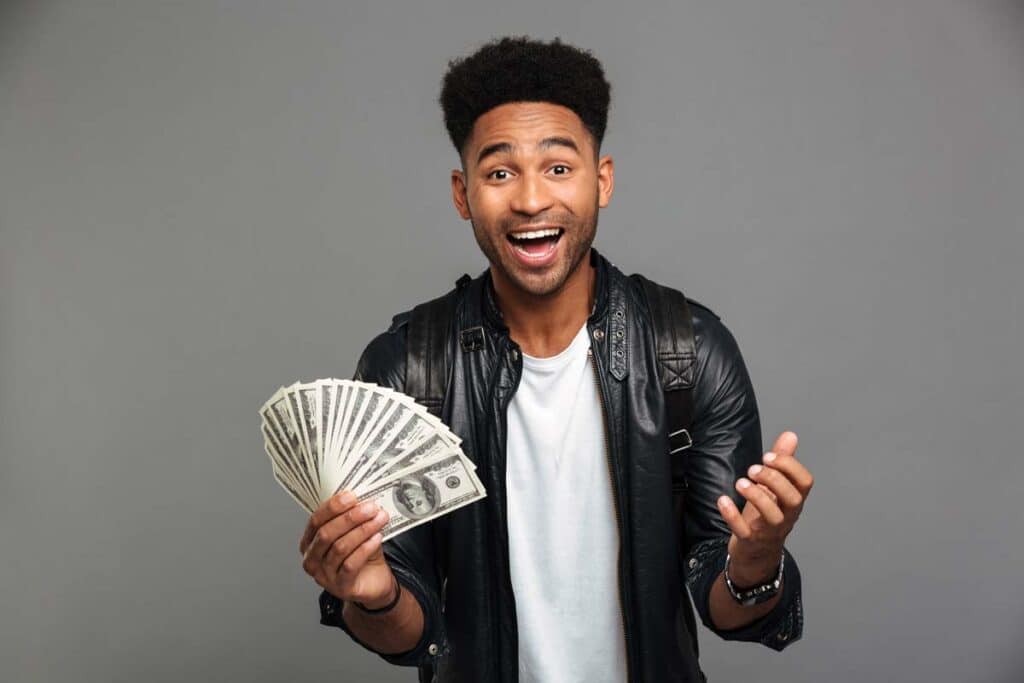 An excited man holding U.S. cash, representing recent settlement payments in the mail.