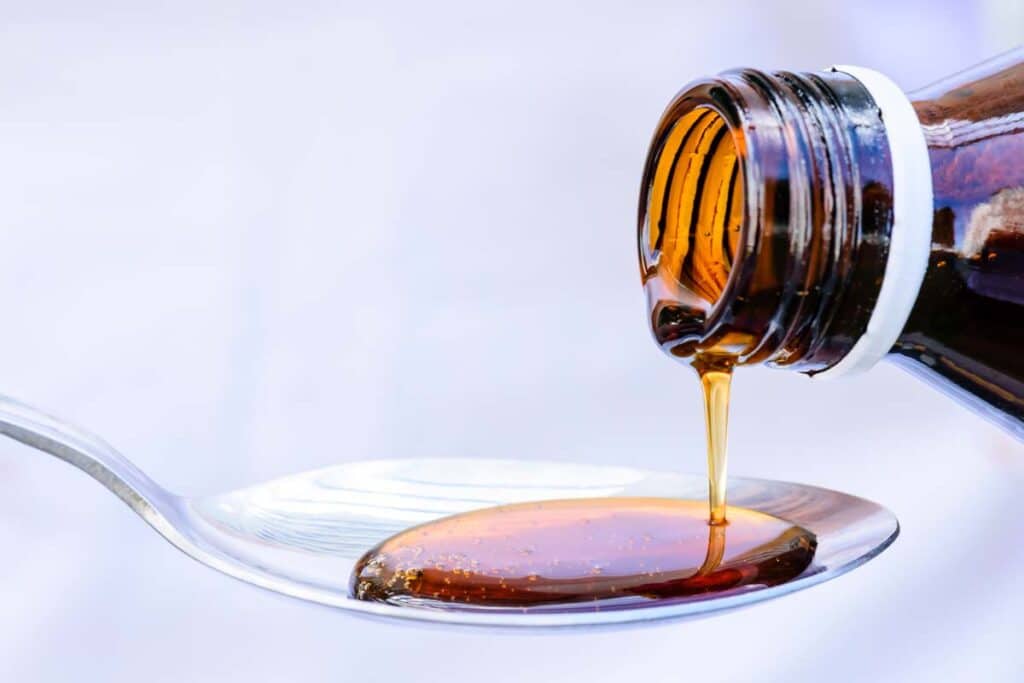 Close up of oral medication solution being poured into a spoon, representing the vancomycin recall.