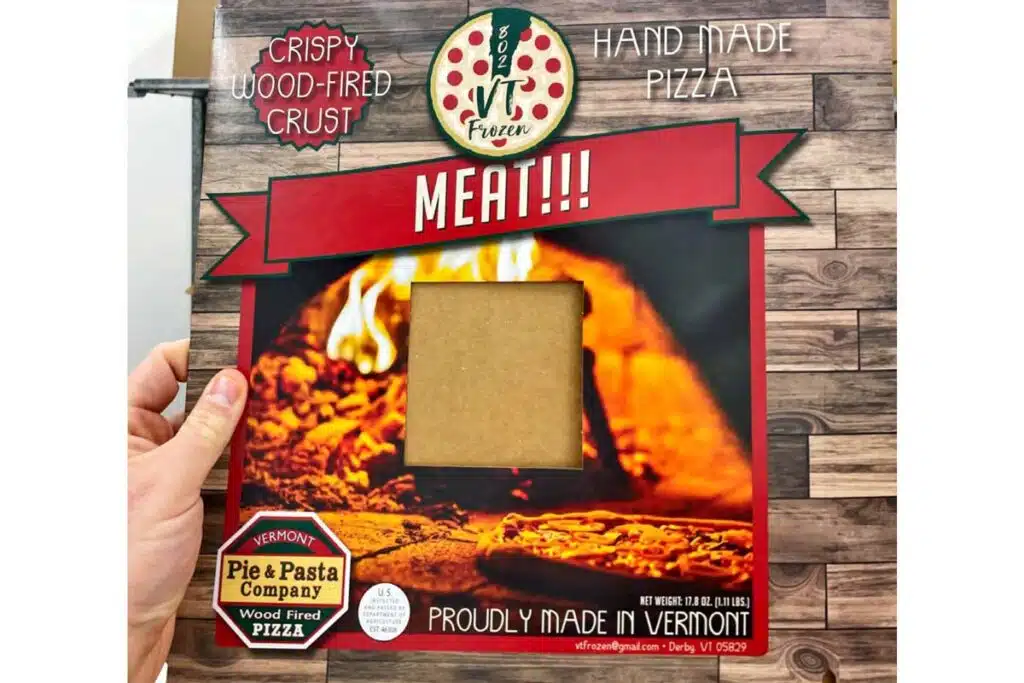 A hand holding product packaging for recalled pizza by 802 VT Frozen representing the frozen pizza recall.