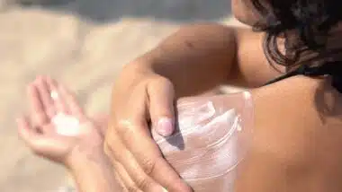 Close up of woman putting sunscreen on her shoulder, representing the sunscreen class actions.