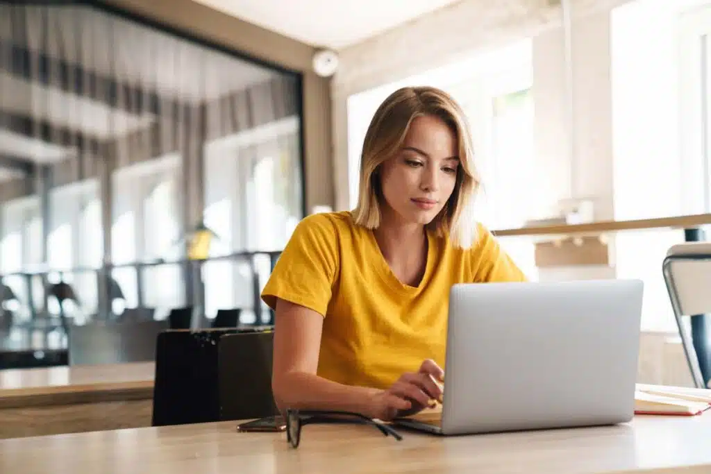 A young woman using a laptop in an office, representing the America's Test Kitchen settlement.