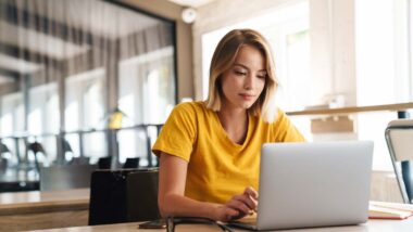 A young woman using a laptop in an office, representing the America's Test Kitchen settlement.