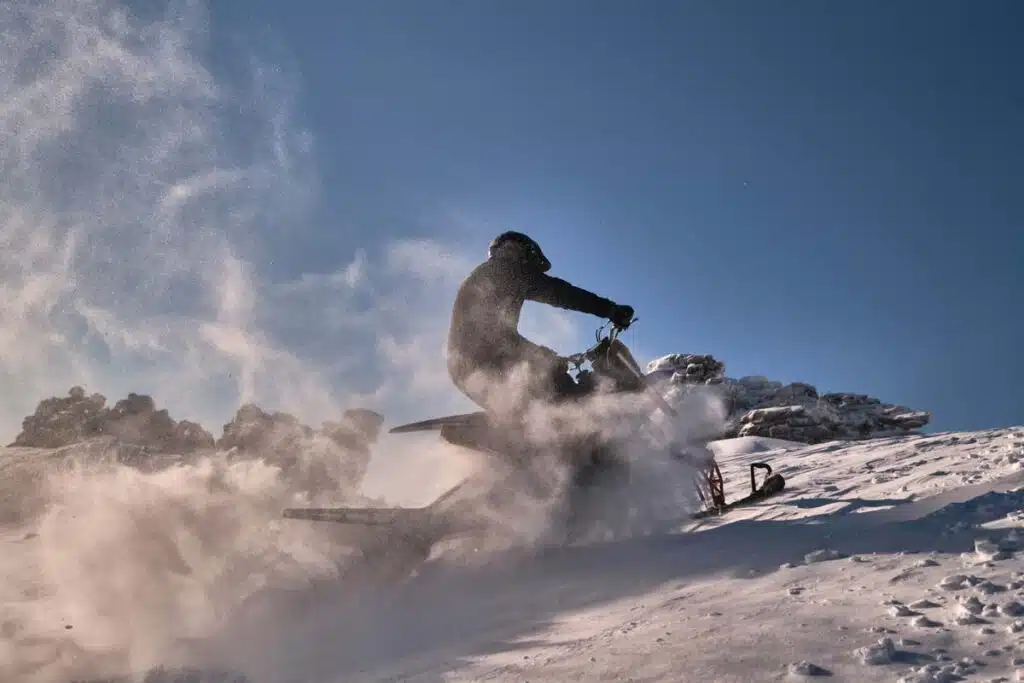 A person riding a snowmobile in a snowy landscape, representing the Arctic Cat recall.