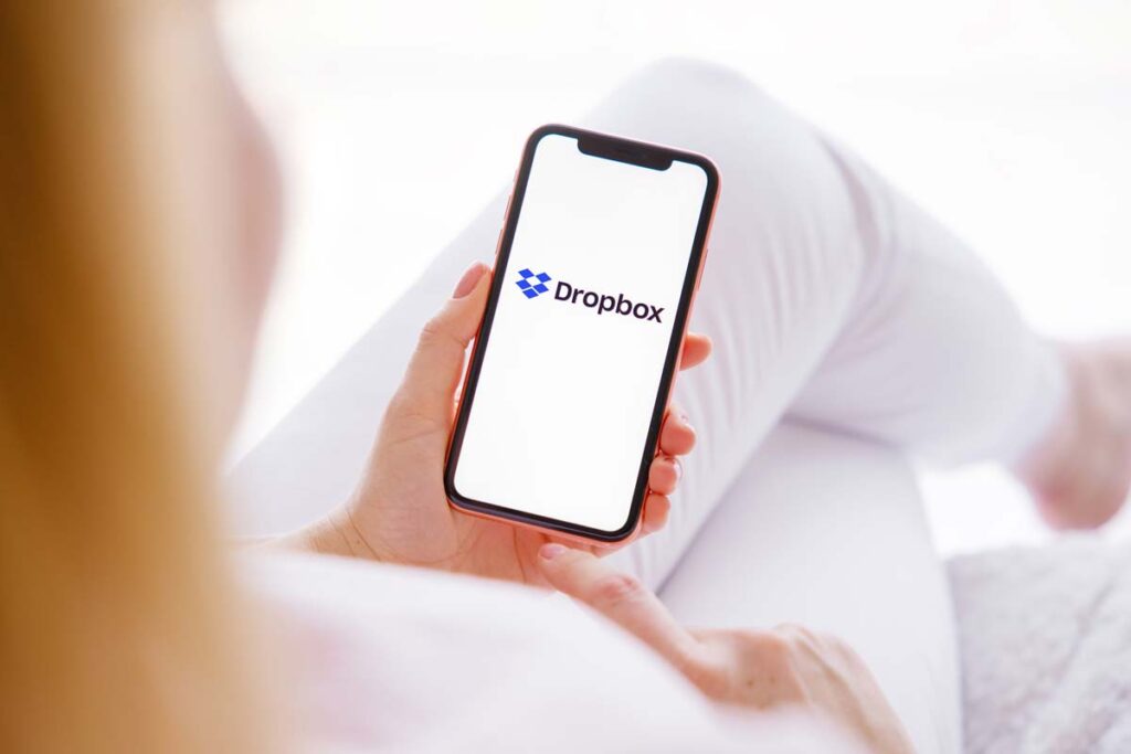 Woman holding a smartphone with the Dropbox logo displayed, representing the Dropbox data breach class action.