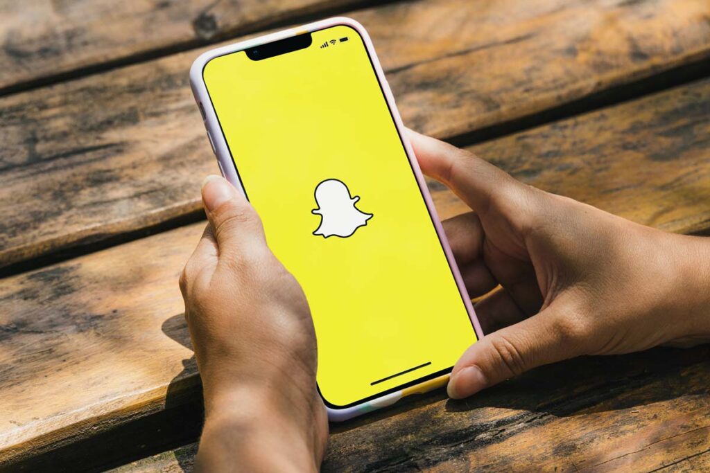 Close up of hands holding a smartphone with Snapchat logo displayed, representing the Snapchat lawsuit.