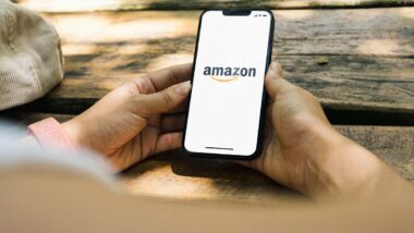 Close up of a man holding a smartphone with the Amazon logo displayed, representing the Amazon Prime cancellation lawsuits.