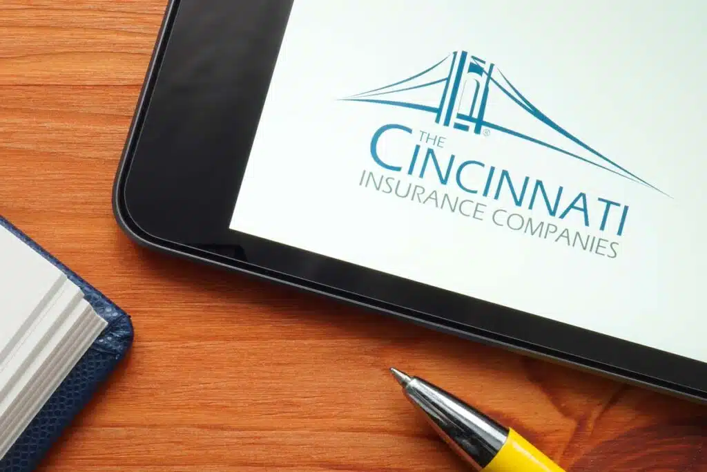 Cincinnati Insurance Companies logo displayed on a tablet next to a pen and journal, representing the Cincinnati Insurance settlement.