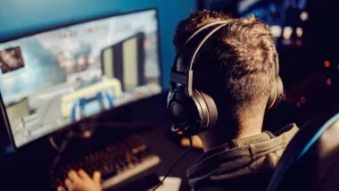 Back view of a young man playing a video game on his computer, representing the video game lawsuit.