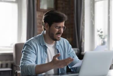 Bank fees have a man upset while doing finances.