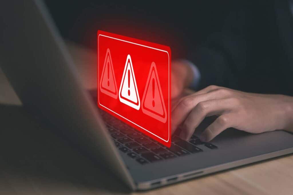 Close up of a man typing on a laptop with a warning symbol data brach concept overlay, representing the Financial Business and Consumer Solutions data breach.