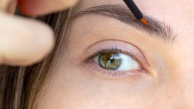 Close up of woman putting a serum on her eyebrows with a brush, representing the Babe lash and brow products.