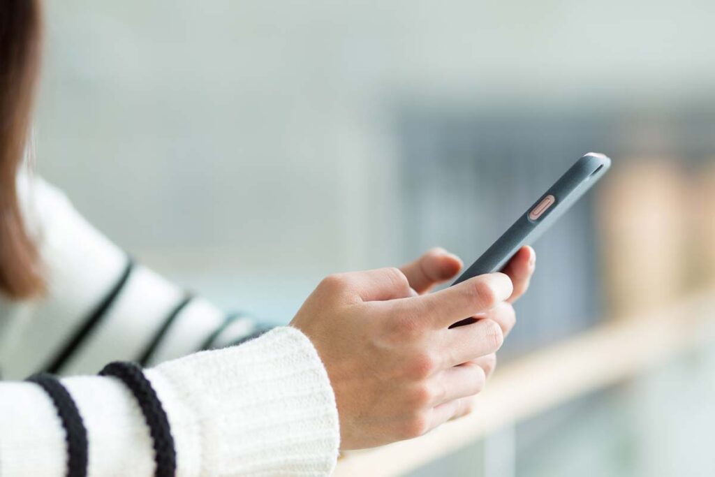 Close up of female hands holding a smartphone, representing the BetterHelp refund.