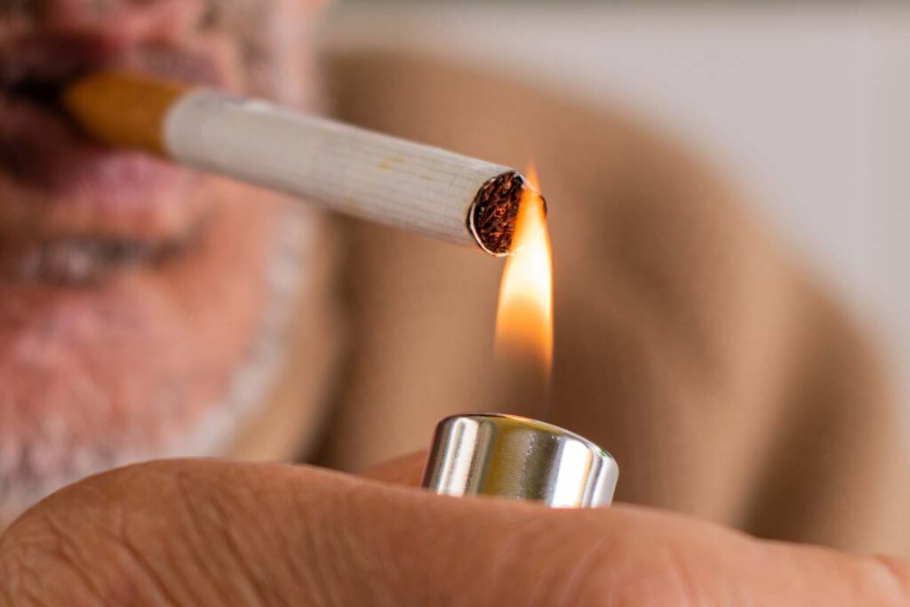 Close up of an elderly man lighting a cigarette, representing the tobacco company verdict.