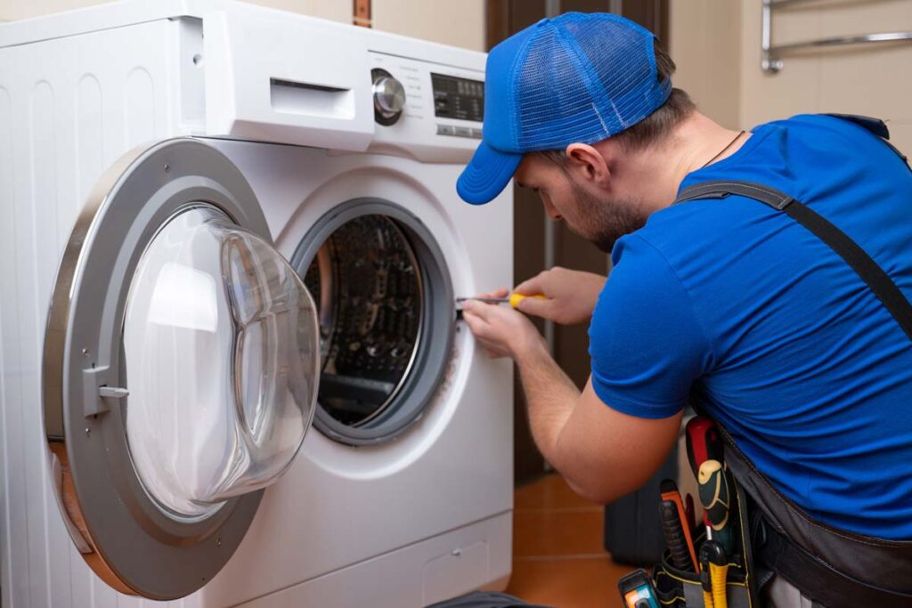 A repairman fixing a washing machine in a residential home, representing the appliance class actions.