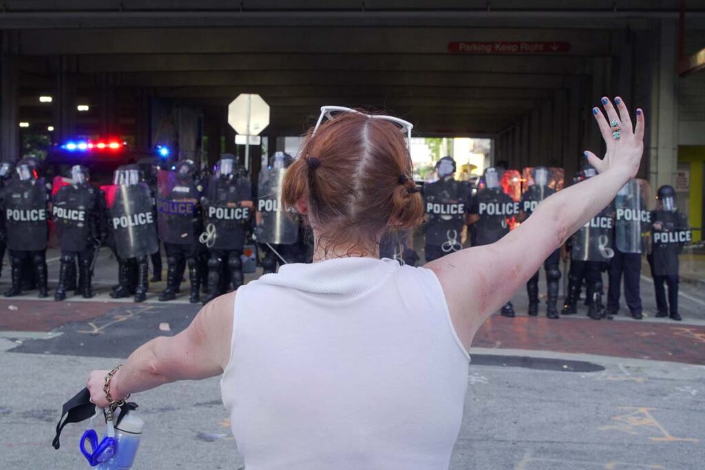 Back view of a woman facing officers at a protest in Ft. Lauderdale on May 31, 2020, representing the Floyd protestors class actions.