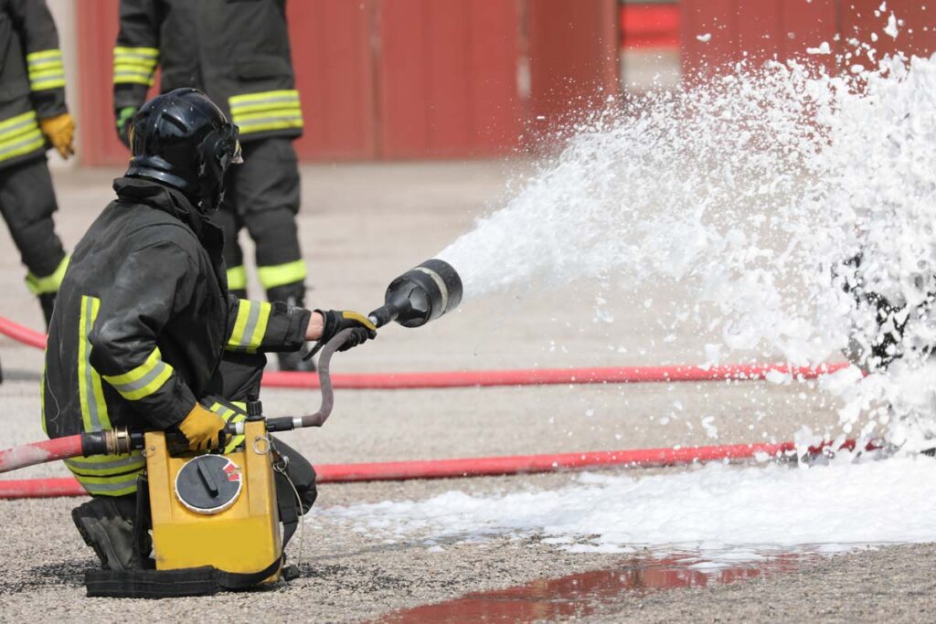 Back view of a firefighter using firefighting foam, representing the Tyco settlement.