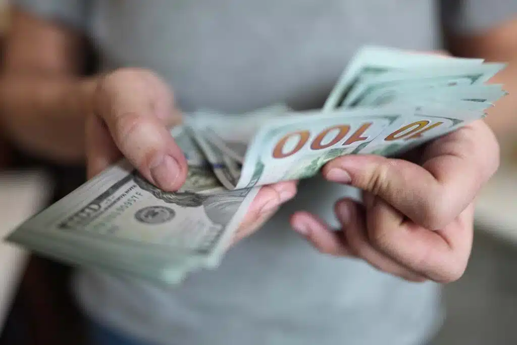 Close up of hands counting U.S. banknotes, representing FTC refunds in May 2024.