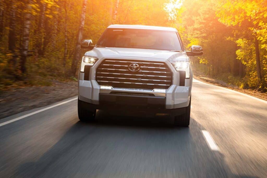 A white Toyota Tundra driving on a scenic road, representing the Toyota recall.