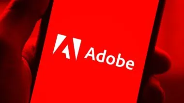 Close up of a hand holding a smartphone with the Adobe logo displayed, representing the FTC lawsuit.