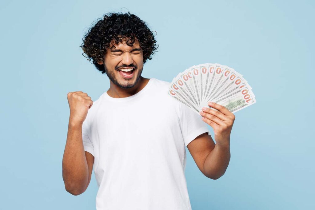 An excited man holding U.S. cash, representing recent settlement checks in the mail.