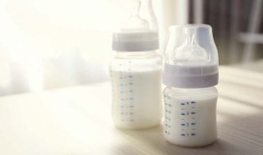 Close up of baby bottles filled with milk on a tabletop, representing the Philips class action.