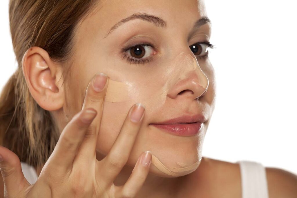 Close up of a woman putting on sunscreen foundation, representing Suntegrity recalls.