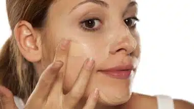 Close up of a woman putting on sunscreen foundation, representing Suntegrity recalls.