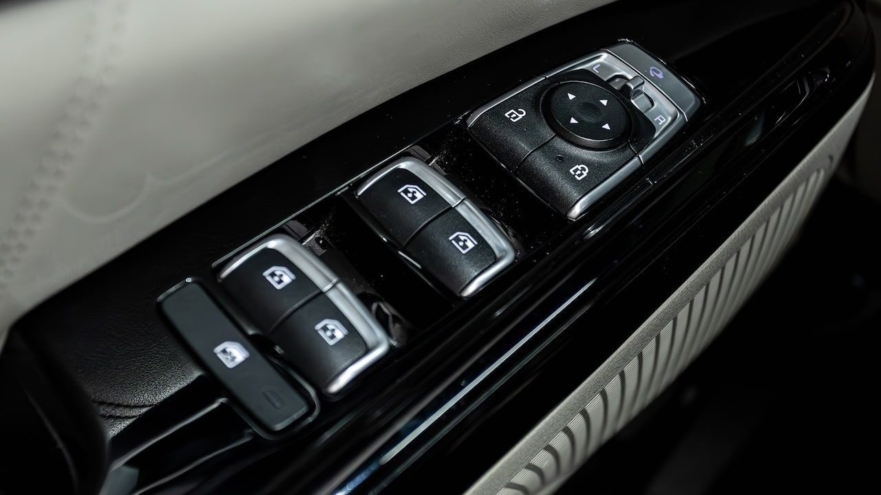 Side door buttons: window, mirror adjustment buttons, door lock. Car inside.