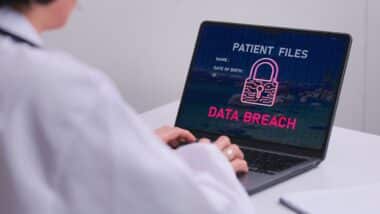 Concerned healthcare doctor looks at laptop screen warning about patient files data breach showing urgent IT security problem on computer