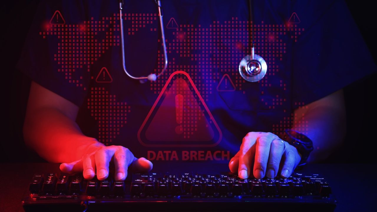 Anxious doctor typing on computer keyboard representing healthcare IT security data breach