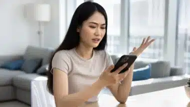 Young woman looks at smartphone screen with dissatisfied expression