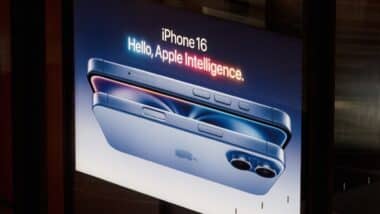 A modern advertising display showcases the sleek design of the new iPhone 16. The illuminated sign emphasizes advanced Apple intelligence, in a urban environment.