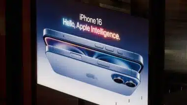 A modern advertising display showcases the sleek design of the new iPhone 16. The illuminated sign emphasizes advanced Apple intelligence, in a urban environment.