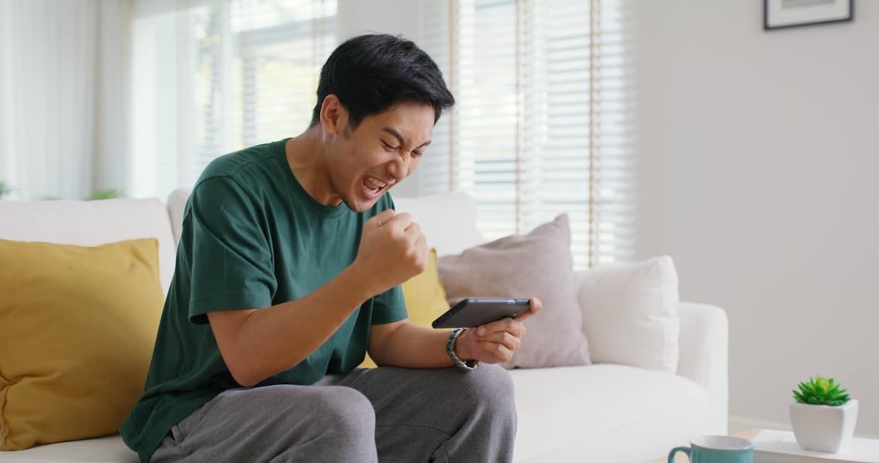 young man sitting at home on sofa couch playing video game gambling.