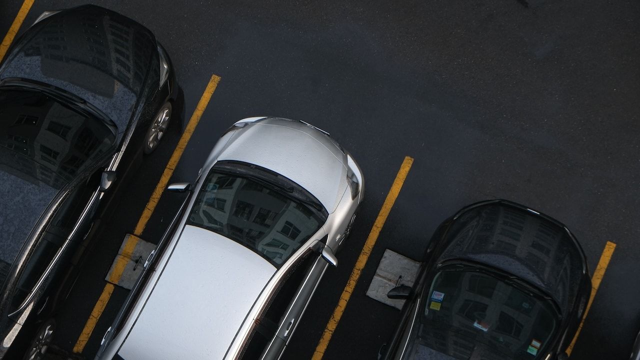 Row of car parking on asphalt lane in modern condominium aerial view