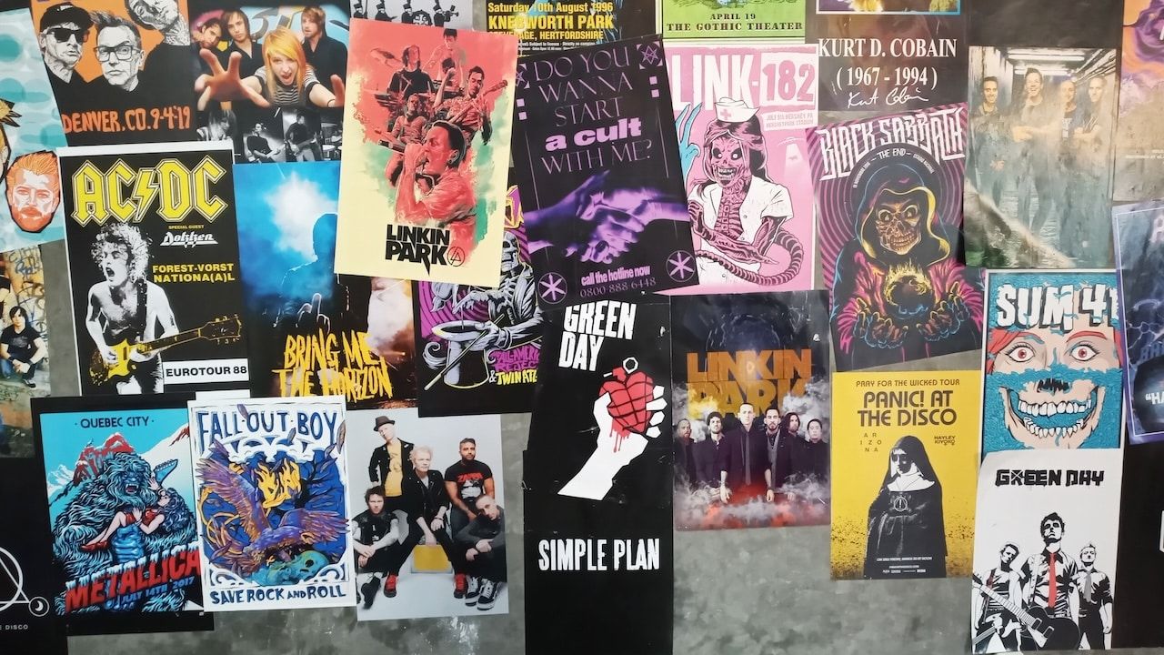 Album posters of various music bands such as Metallica, Green Day, Linkin Park, Sum41, Simple Plan, AC-DC, and so on, attached to concrete walls.