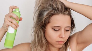 A young woman putting dry shampoo in her hair, representing the IGK dry shampoo settlement.