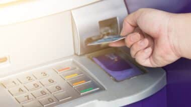 Hand inserting ATM credit card into bank machine
